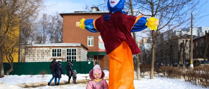 Маленький ребенок стоит рядом с чучелом из соломы, Масленица в Ивантеевке