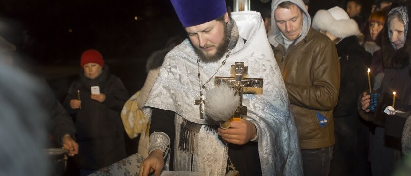 Священник стоит над иконой и священной книгой, Крещение в Пушкине, Московская область