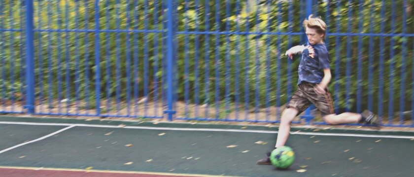 Мальчик, играющий в футбол на новой площадке