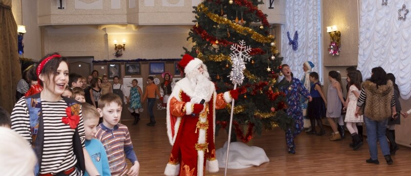 Дед Мороз, Снегурочка и другие сказочные персонажи водят хоровод вместе с детьми вокруг елки 