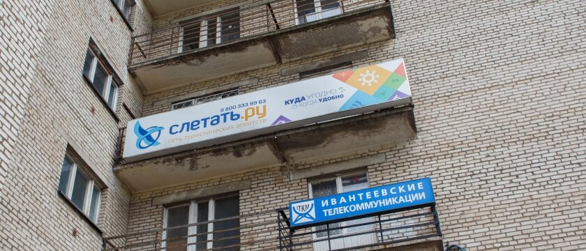 На балконе дома висит баннер турфирмы "Слетать.ру", туризм, Ивантеевка, Московская область