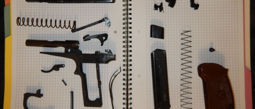 Пистолет разобран на все составляющие: пружины, курок, рукоятка, ствол, магазин и другие
