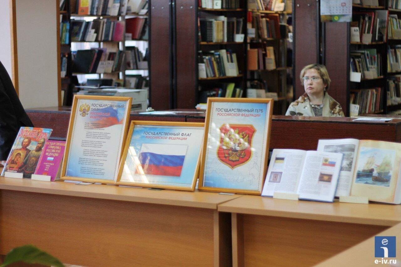 Флаг России, текст гимна России, герб России, стоят в рамке на столе