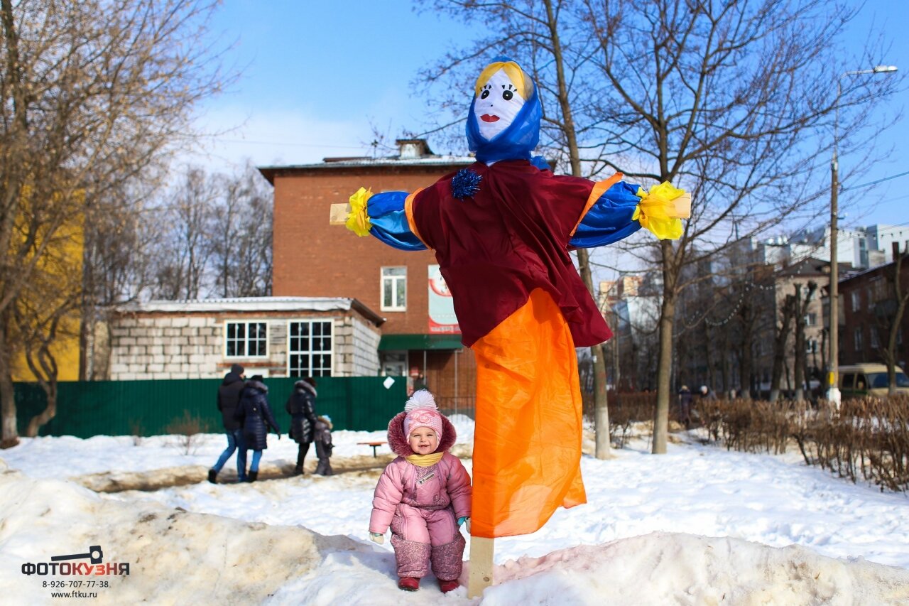 Маленький ребенок стоит рядом с чучелом из соломы, Масленица в Ивантеевке
