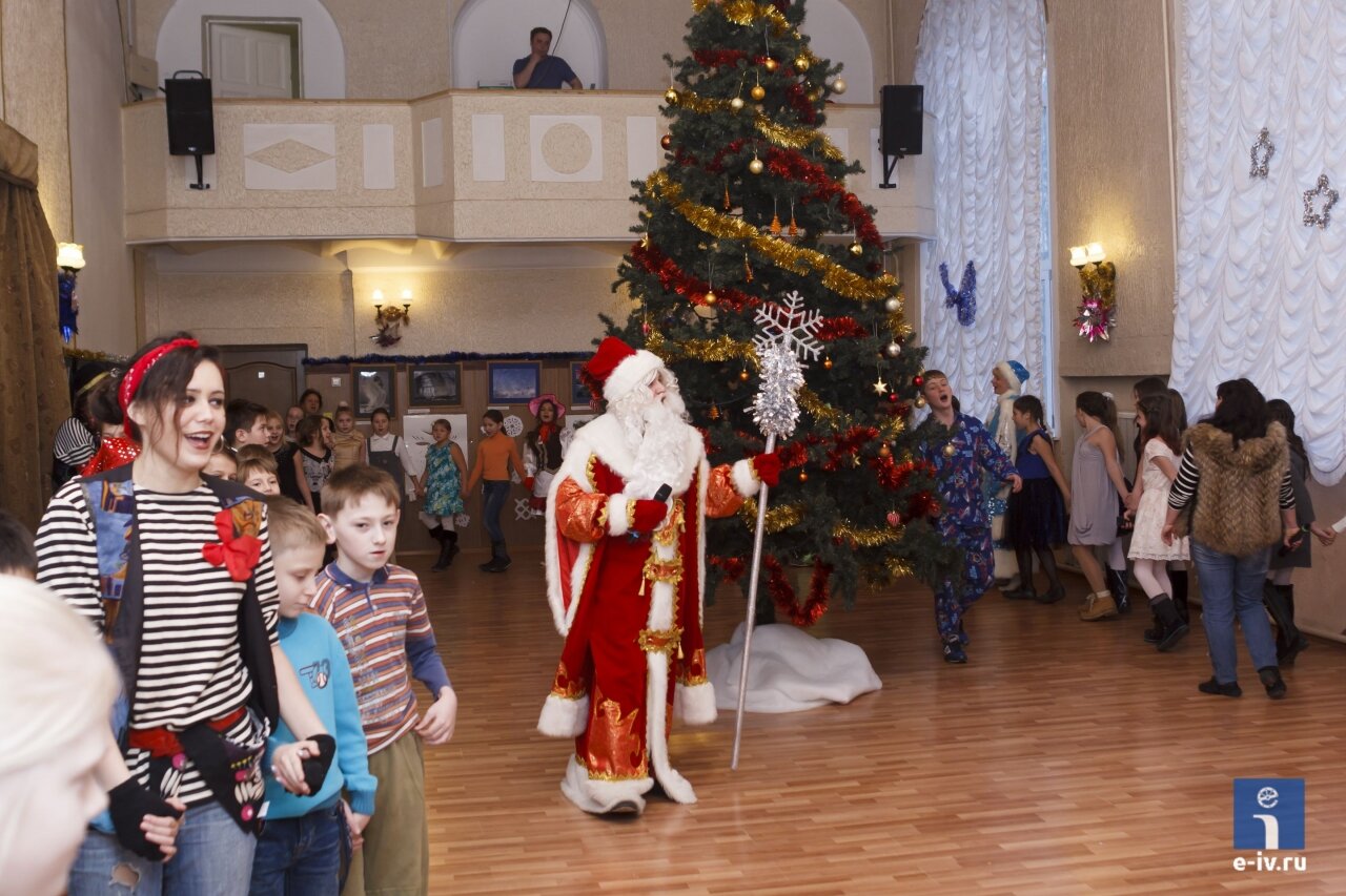 Дед Мороз, Снегурочка и другие сказочные персонажи водят хоровод вместе с детьми вокруг елки 